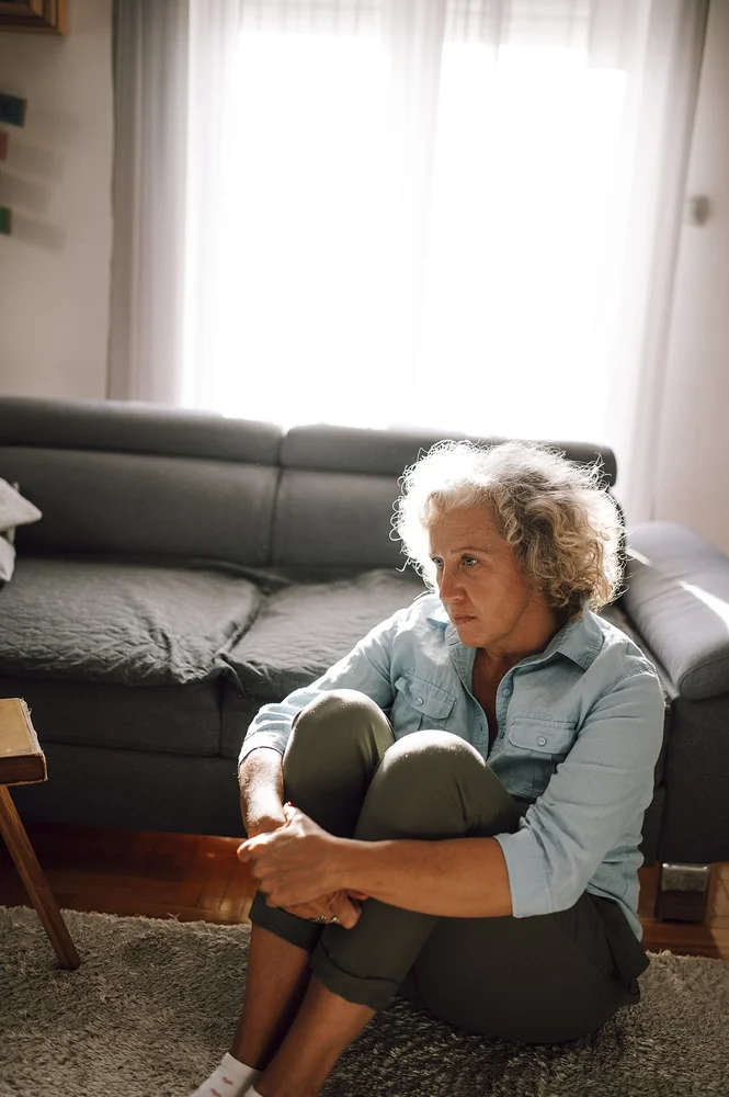 angry facial expression photo — Woman sitting on the floor of a cozy living room